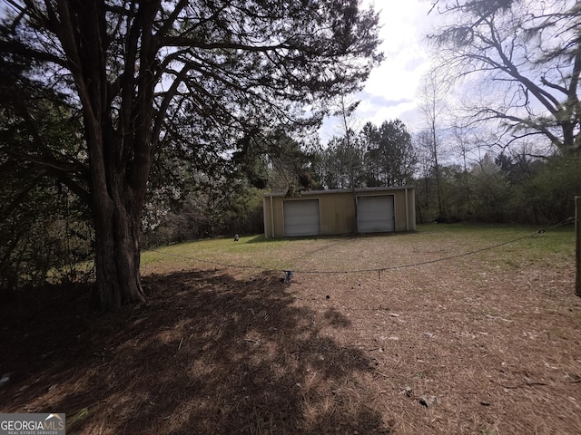 view of yard featuring driveway, a detached garage, and an outdoor structure