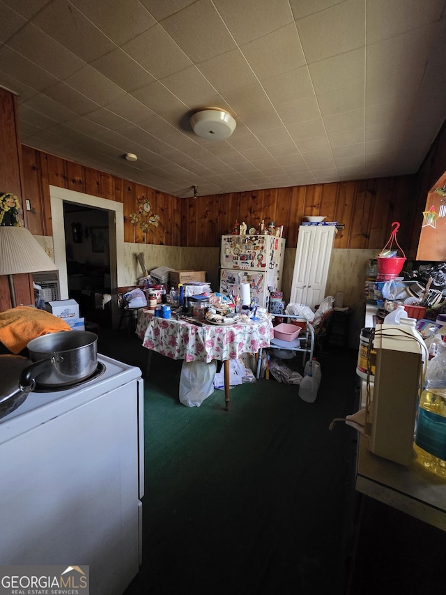 bedroom featuring carpet flooring, freestanding refrigerator, washer / clothes dryer, and wood walls