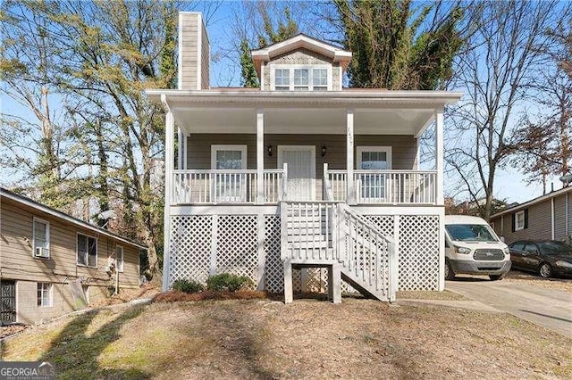 view of front facade with stairway, covered porch, and a chimney