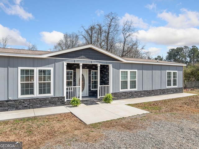 view of front of home featuring covered porch and stone siding