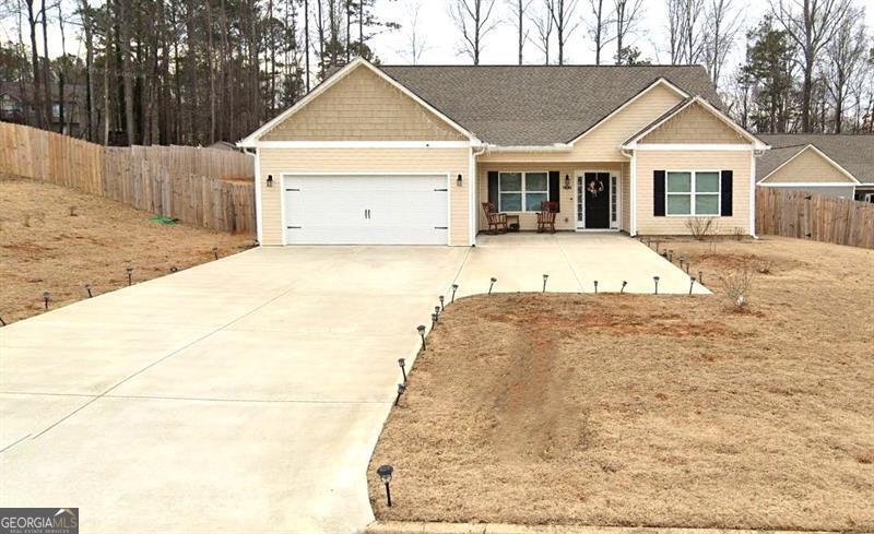 view of front of home featuring an attached garage, concrete driveway, and fence