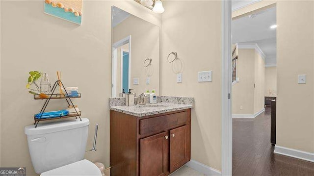 bathroom featuring toilet, vanity, baseboards, and ornamental molding