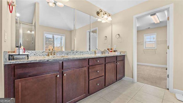 full bathroom featuring baseboards, double vanity, a sink, a shower stall, and tile patterned floors