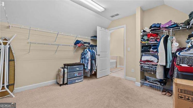 spacious closet with visible vents, lofted ceiling, and carpet flooring