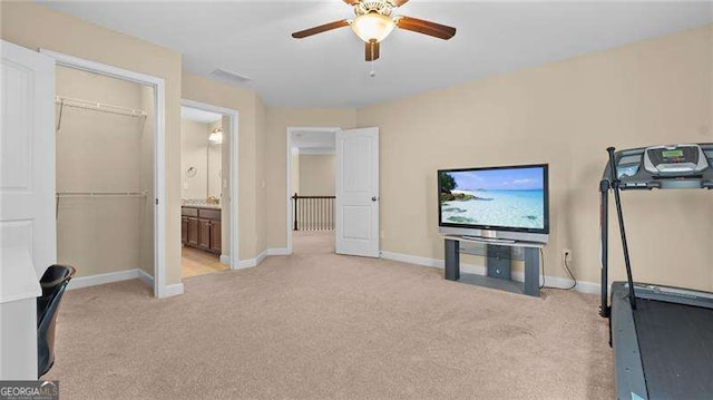 workout room with a ceiling fan, light colored carpet, and baseboards