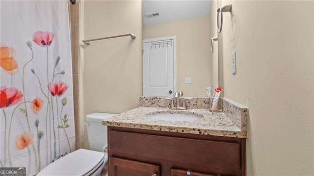 bathroom featuring a shower with shower curtain, visible vents, toilet, and vanity