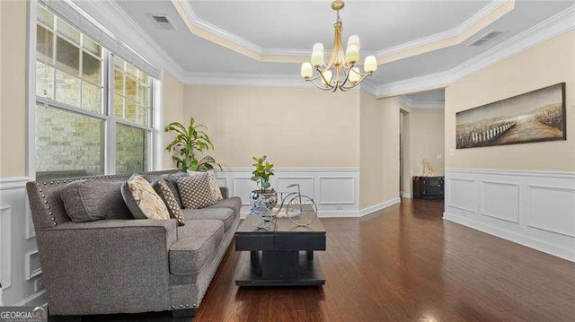 living area featuring a chandelier, visible vents, a tray ceiling, and wood finished floors