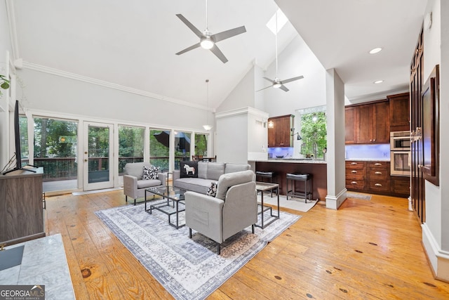 living room with plenty of natural light, high vaulted ceiling, light wood-style flooring, and a ceiling fan