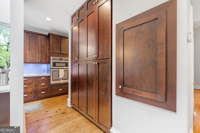 kitchen featuring double oven, light countertops, recessed lighting, and light wood finished floors