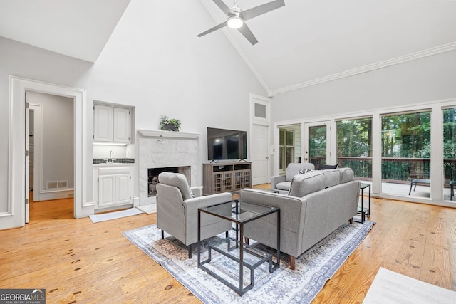 living area with visible vents, ceiling fan, high vaulted ceiling, and light wood-style floors