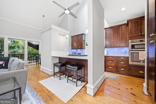 kitchen with decorative backsplash, baseboards, a breakfast bar, and light wood-style flooring