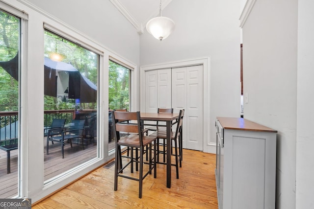 dining room with light wood-type flooring and crown molding