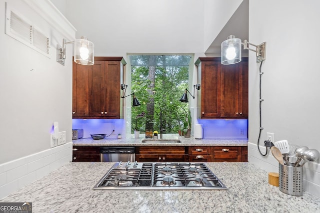 kitchen with a sink, stainless steel appliances, and light stone counters