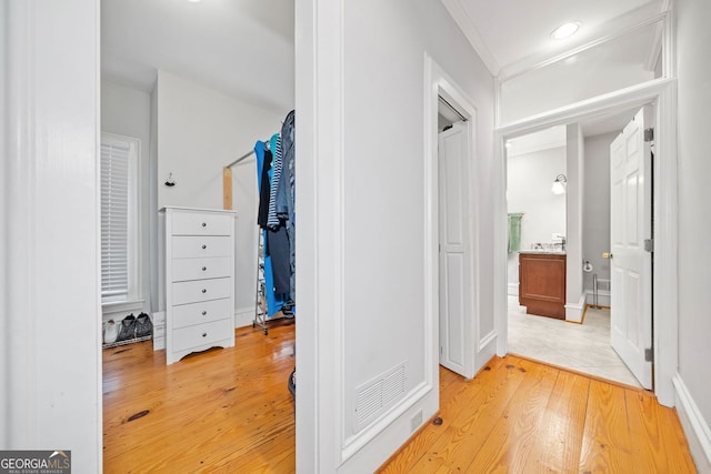 hall featuring light wood finished floors, visible vents, recessed lighting, and crown molding