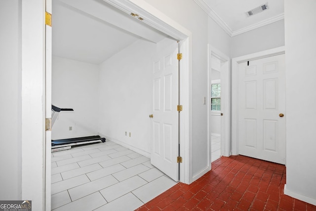 foyer entrance with brick floor, visible vents, baseboards, and crown molding