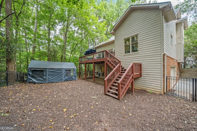 back of house with stairway, fence, an attached garage, a deck, and brick siding