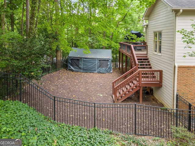 view of yard featuring a covered hot tub, dirt driveway, stairway, a fenced backyard, and a deck