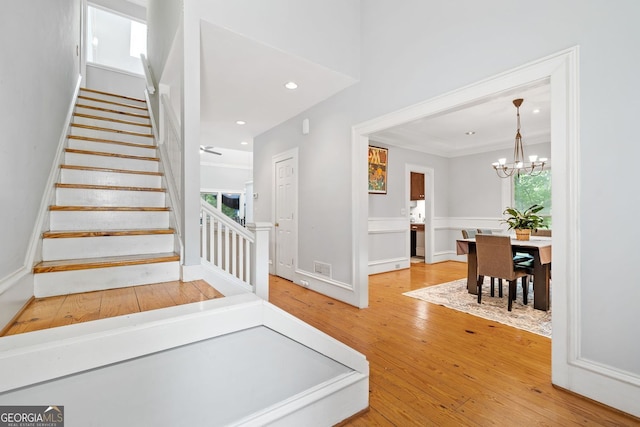 stairs with visible vents, a notable chandelier, ornamental molding, hardwood / wood-style floors, and recessed lighting