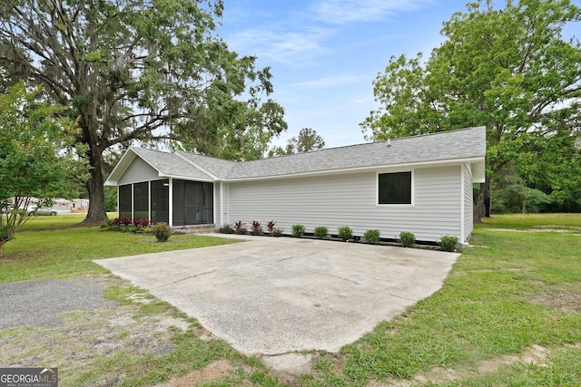 view of front of home with a sunroom, a front yard, and roof with shingles