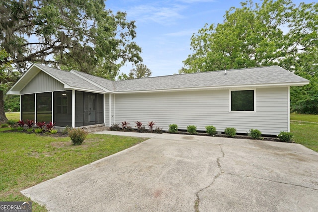 single story home featuring a sunroom, a shingled roof, and a front yard