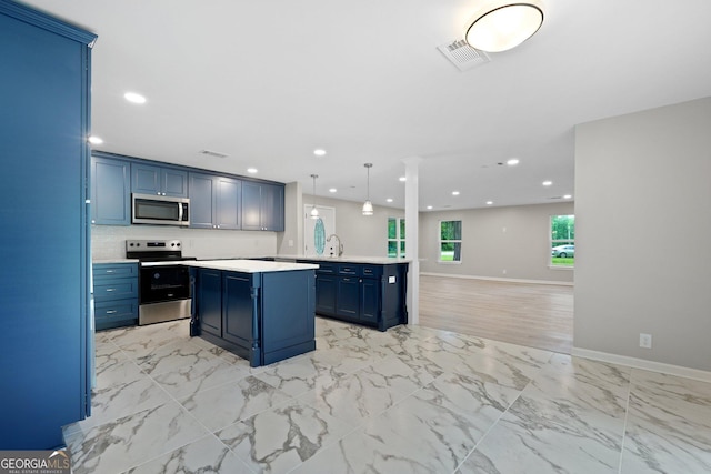 kitchen with stainless steel appliances, blue cabinetry, open floor plan, light countertops, and a kitchen island