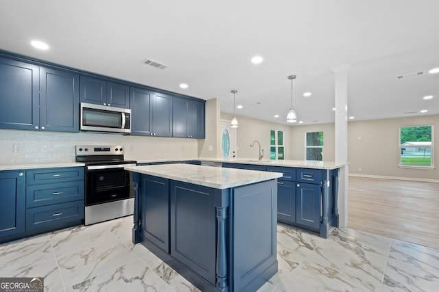 kitchen featuring appliances with stainless steel finishes, a peninsula, a center island, blue cabinets, and a sink