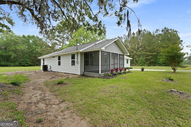 rear view of property featuring a sunroom, a yard, a shingled roof, and central AC unit