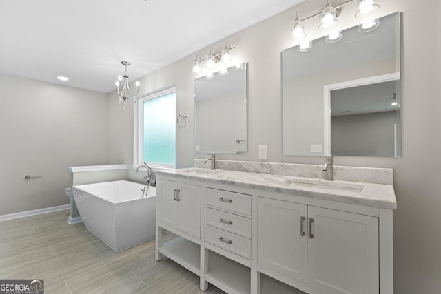 bathroom with double vanity, a freestanding tub, a chandelier, baseboards, and wood finished floors