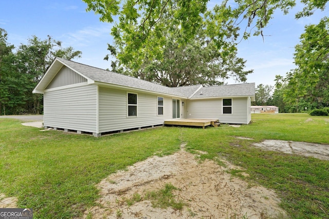 back of property featuring a yard, a wooden deck, and a shingled roof