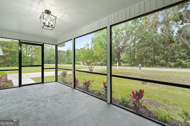 unfurnished sunroom featuring a chandelier and view of scattered trees