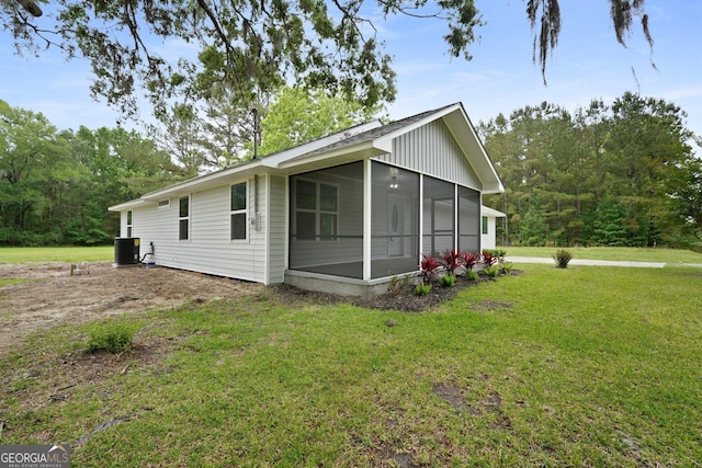 view of side of property featuring a sunroom, a yard, and central AC