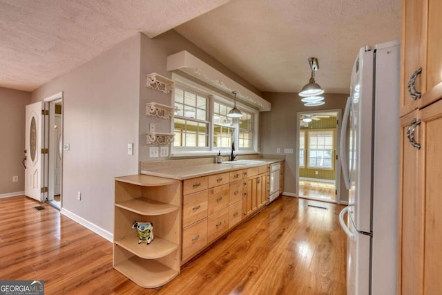 kitchen featuring a sink, light wood-type flooring, light countertops, white appliances, and open shelves