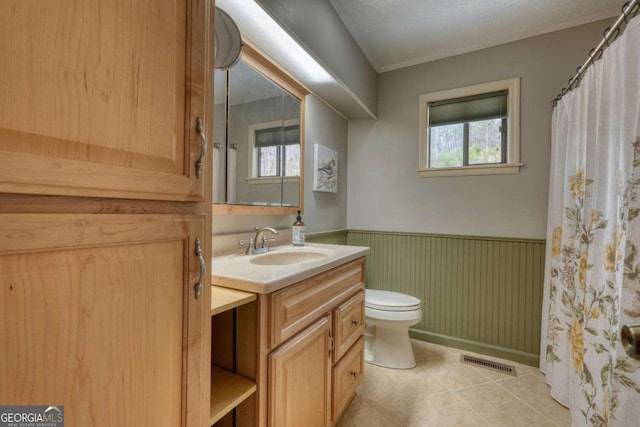 bathroom featuring vanity, visible vents, tile patterned flooring, wainscoting, and toilet