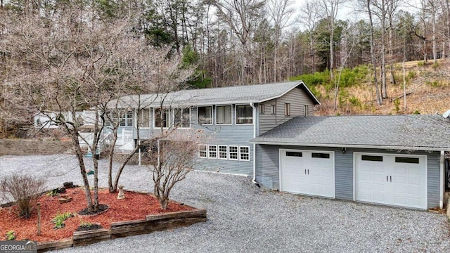 traditional home with driveway, a garage, and roof with shingles