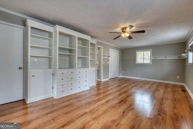 interior space featuring ornamental molding, wood finished floors, wainscoting, and a textured ceiling