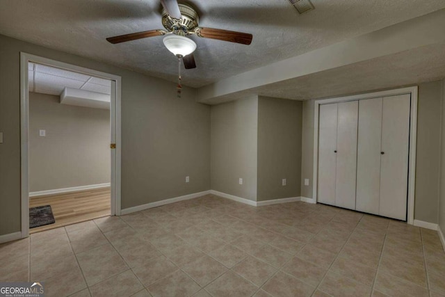 unfurnished bedroom with light tile patterned floors, a ceiling fan, baseboards, visible vents, and a textured ceiling