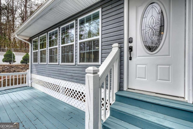 entrance to property featuring fence and a wooden deck