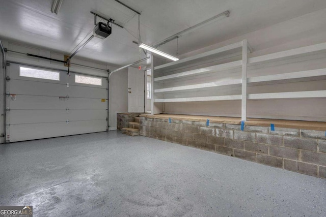 garage featuring concrete block wall and a garage door opener