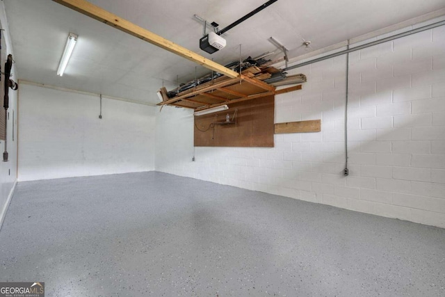 garage featuring a garage door opener and concrete block wall