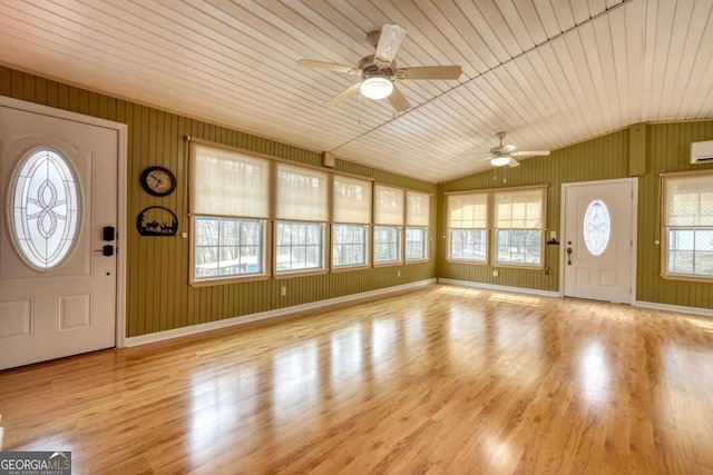 entryway featuring an AC wall unit, wood finished floors, baseboards, ceiling fan, and vaulted ceiling