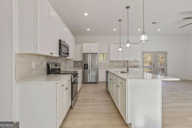 kitchen with a sink, light countertops, french doors, light wood-style floors, and appliances with stainless steel finishes