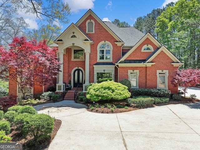 view of front of house featuring french doors, brick siding, and roof with shingles