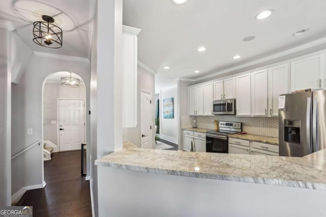 kitchen with arched walkways, tasteful backsplash, appliances with stainless steel finishes, and ornamental molding