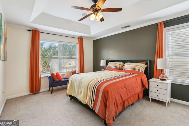 carpeted bedroom with a tray ceiling, baseboards, visible vents, and ceiling fan