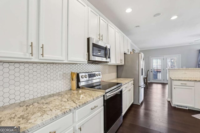 kitchen with dark wood-type flooring, light stone countertops, decorative backsplash, appliances with stainless steel finishes, and white cabinetry