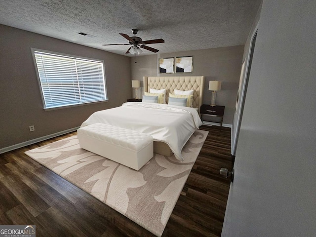 bedroom with visible vents, baseboards, a textured ceiling, and wood finished floors