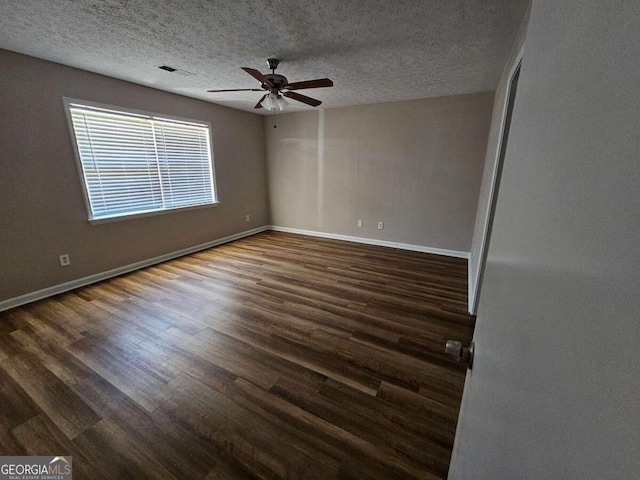 empty room featuring dark wood finished floors, visible vents, baseboards, and a ceiling fan