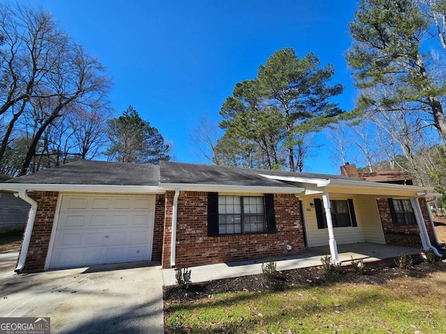 ranch-style home with brick siding, an attached garage, a chimney, and driveway