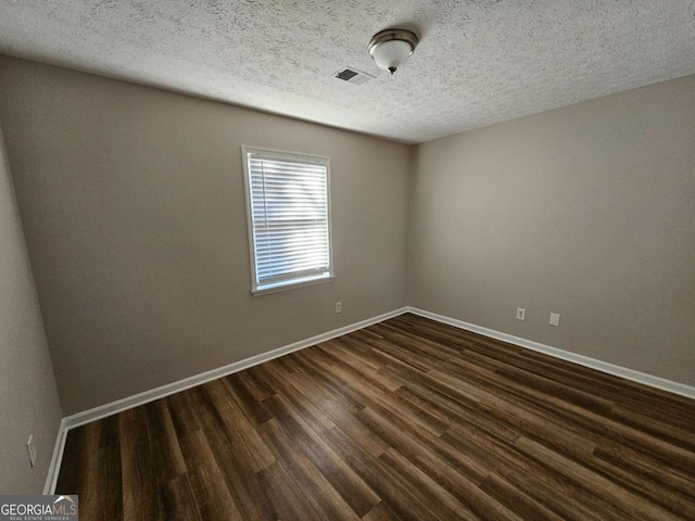 spare room with baseboards, visible vents, dark wood-style flooring, and a textured ceiling