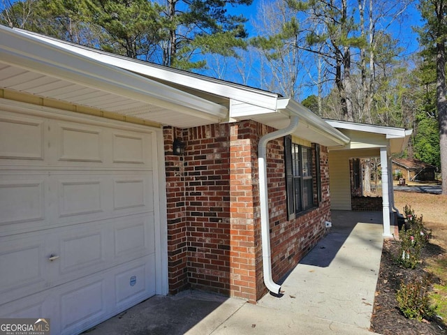 doorway to property with a garage and brick siding